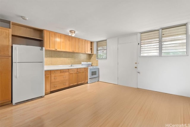 kitchen featuring sink, backsplash, white appliances, and light hardwood / wood-style floors