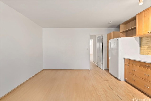 kitchen with white refrigerator, light hardwood / wood-style floors, and decorative backsplash