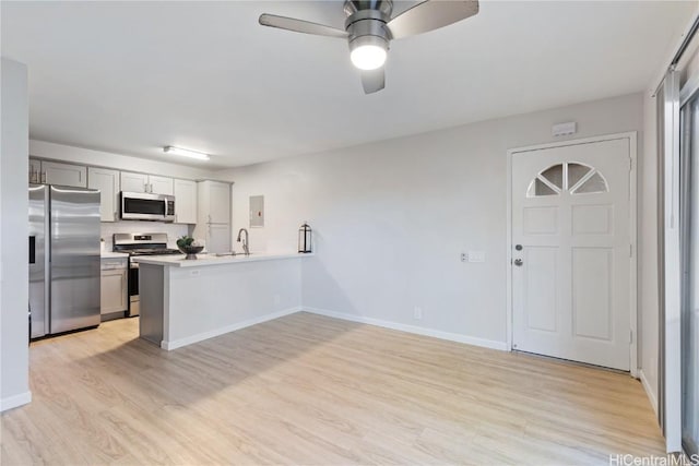 kitchen featuring ceiling fan, sink, kitchen peninsula, appliances with stainless steel finishes, and light wood-type flooring