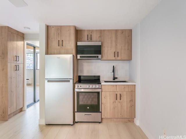 kitchen featuring light brown cabinets, sink, light hardwood / wood-style flooring, decorative backsplash, and stainless steel appliances