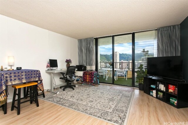 home office with hardwood / wood-style floors, a textured ceiling, and a wall of windows