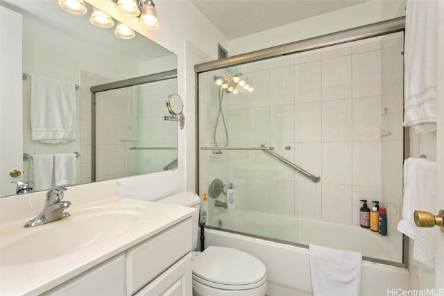 full bathroom with combined bath / shower with glass door, vanity, and toilet