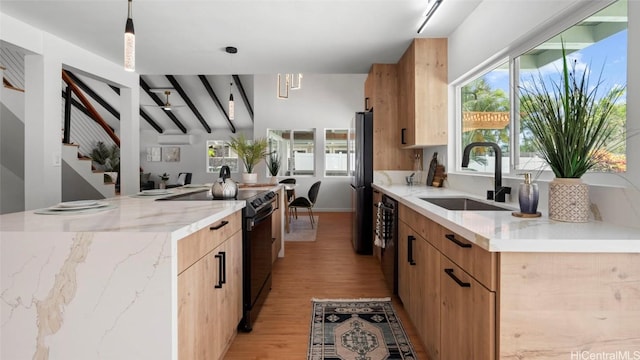 kitchen featuring light stone countertops, sink, decorative light fixtures, and black appliances