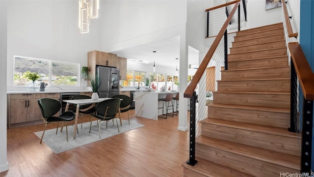 dining space with beverage cooler, a high ceiling, and light wood-type flooring