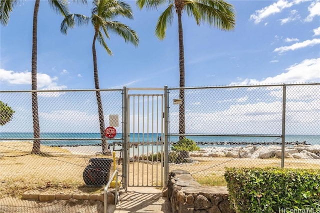 exterior space featuring a water view, a view of the beach, a gate, and fence