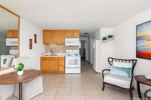 kitchen with white appliances, tasteful backsplash, light tile patterned floors, light countertops, and a sink