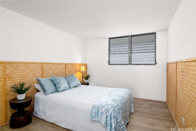 bedroom featuring wainscoting and wood finished floors