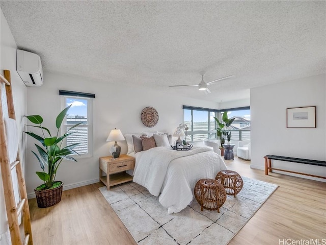 bedroom with multiple windows, a textured ceiling, a wall unit AC, and ceiling fan