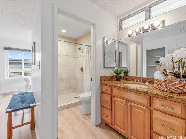 bathroom featuring a shower with shower curtain, hardwood / wood-style floors, a textured ceiling, and toilet