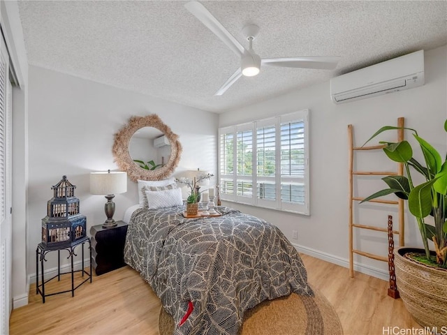 bedroom with a textured ceiling, ceiling fan, a closet, and a wall mounted air conditioner