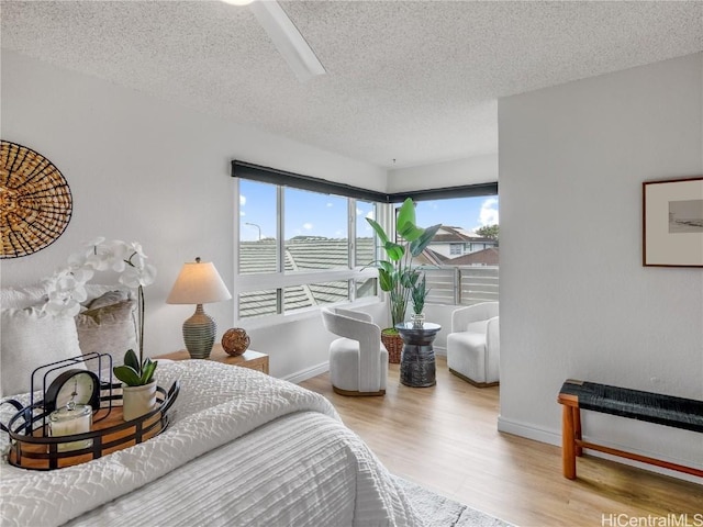 bedroom with ceiling fan, light hardwood / wood-style floors, and a textured ceiling