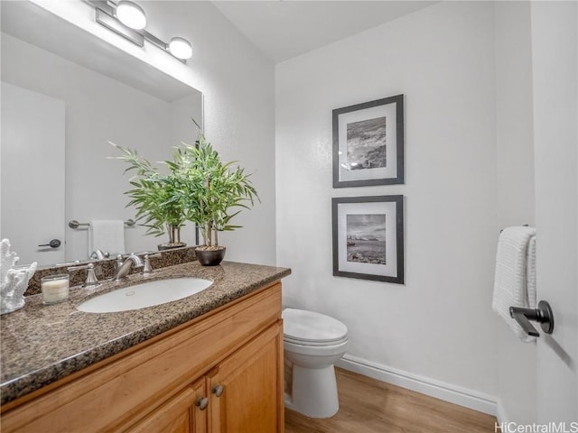 bathroom with toilet, vanity, and hardwood / wood-style flooring