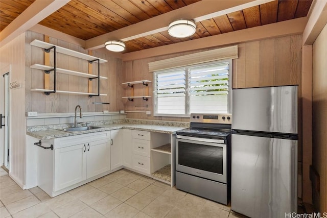 kitchen with sink, white cabinets, light tile patterned flooring, wood walls, and stainless steel appliances