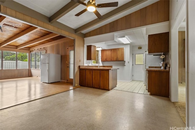 kitchen featuring vaulted ceiling with beams, sink, kitchen peninsula, refrigerator, and ceiling fan