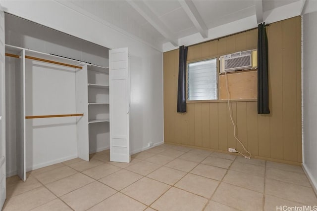 unfurnished bedroom featuring light tile patterned floors, wood walls, a wall mounted AC, and vaulted ceiling with beams