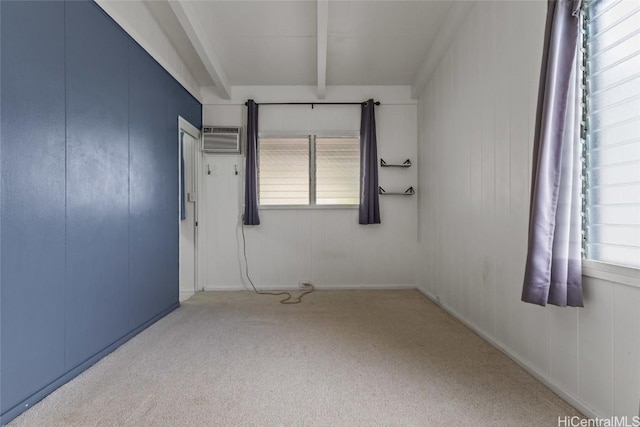 carpeted spare room featuring a wall mounted air conditioner, a wealth of natural light, and beam ceiling