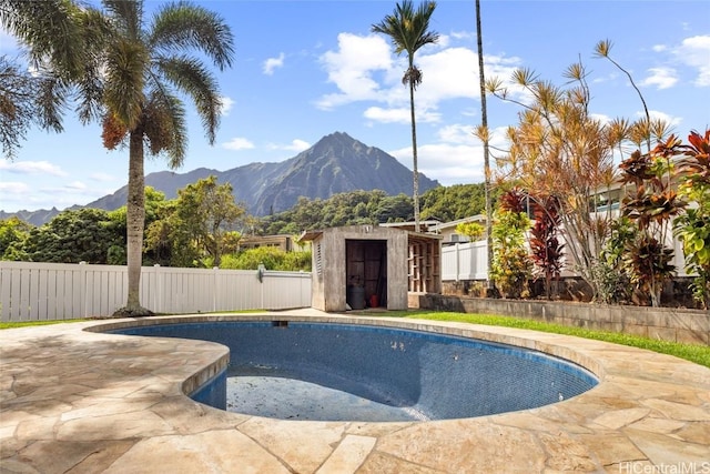 view of pool featuring a mountain view, a patio area, and a storage shed