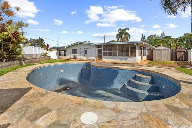 view of swimming pool featuring a patio, a shed, and a sunroom