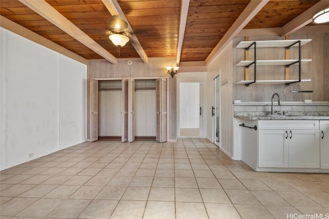 kitchen featuring wood ceiling, light tile patterned floors, white cabinets, beam ceiling, and light stone counters