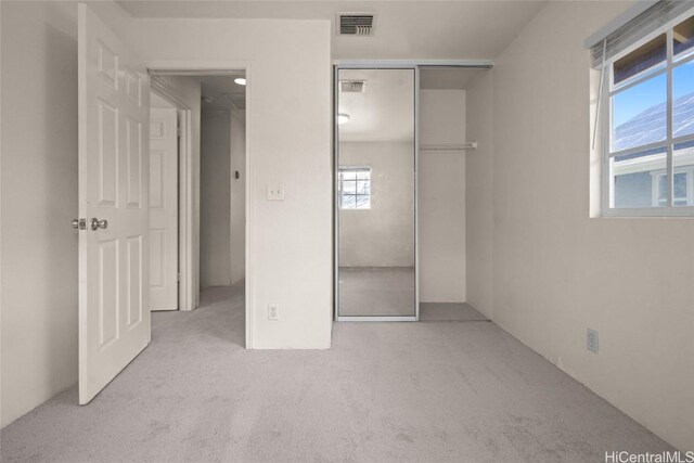 unfurnished bedroom featuring light carpet and a closet