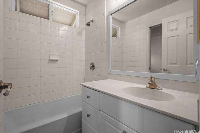 bathroom with tiled shower / bath combo and vanity