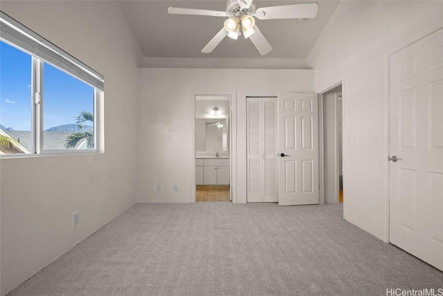 unfurnished bedroom with connected bathroom, light carpet, ceiling fan, and a closet