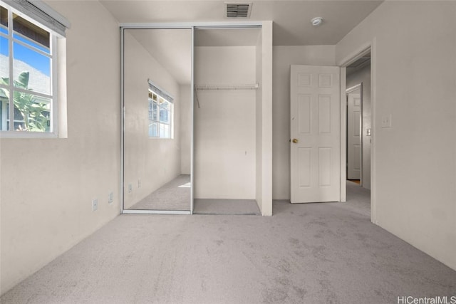 unfurnished bedroom featuring light carpet and a closet