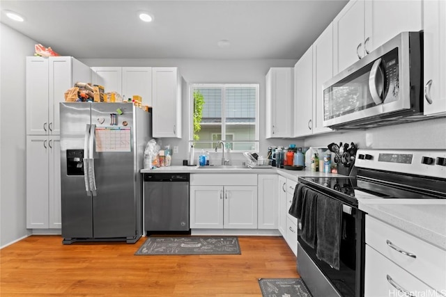 kitchen featuring white cabinets, light wood-type flooring, sink, and appliances with stainless steel finishes