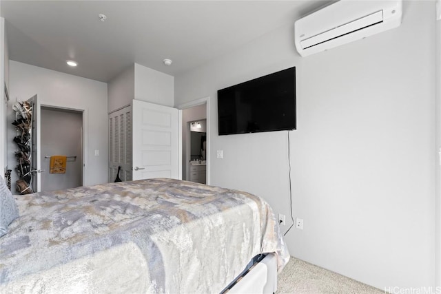 bedroom featuring connected bathroom, a closet, carpet, and a wall mounted air conditioner