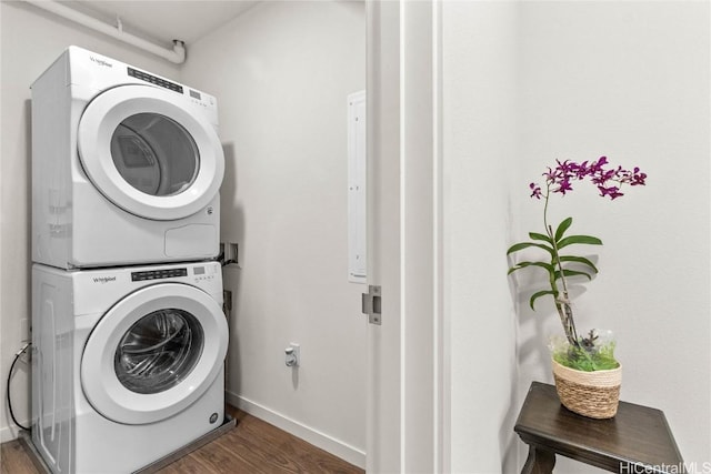 laundry room featuring dark wood-type flooring and stacked washer / dryer