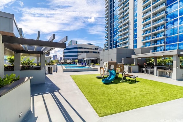 view of swimming pool featuring a playground, a patio, and a lawn