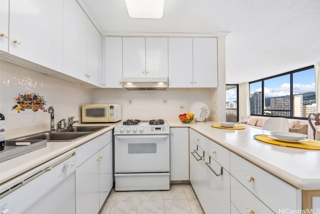 kitchen with white appliances, sink, kitchen peninsula, light tile patterned flooring, and white cabinetry