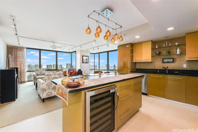 kitchen featuring a kitchen island with sink, wine cooler, stainless steel dishwasher, ceiling fan, and a wall of windows