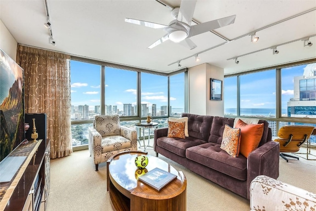 living room featuring ceiling fan, a water view, light carpet, and a wall of windows