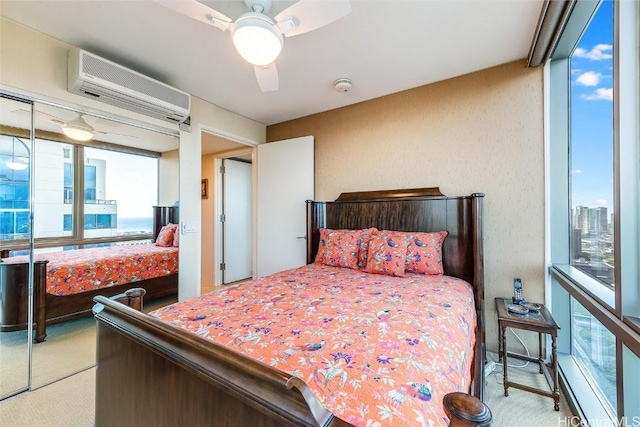 carpeted bedroom with a wall mounted AC, ceiling fan, and a closet