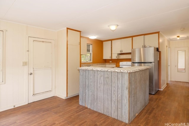 kitchen featuring dark wood-type flooring, electric range, a center island, and stainless steel refrigerator