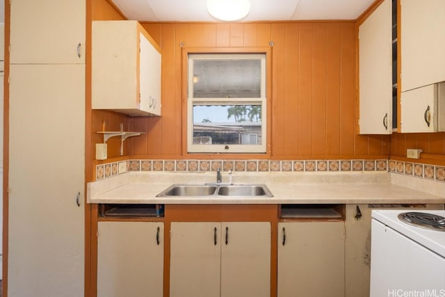 kitchen with sink, electric stove, white cabinets, and wood walls