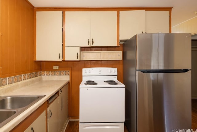 kitchen featuring white cabinets, white electric stove, wooden walls, sink, and stainless steel fridge