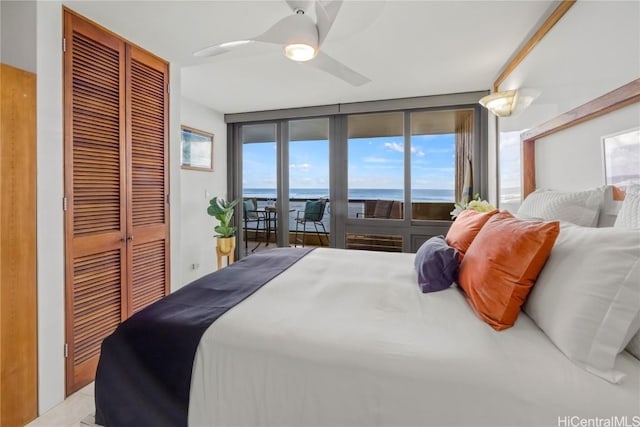 bedroom featuring access to exterior, a water view, a wall of windows, and ceiling fan