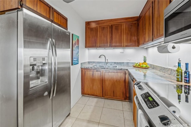 kitchen featuring light stone counters, sink, light tile patterned floors, and stainless steel appliances