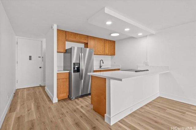 kitchen featuring sink, light hardwood / wood-style flooring, stainless steel fridge, and kitchen peninsula