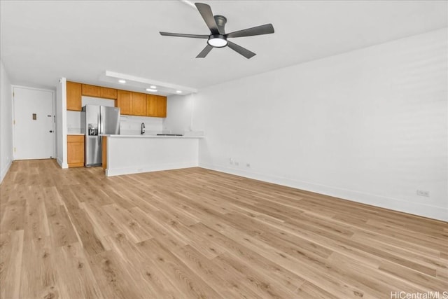 unfurnished living room with ceiling fan, sink, and light hardwood / wood-style floors