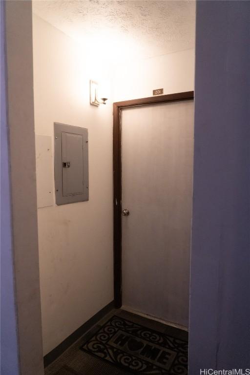 doorway featuring electric panel and a textured ceiling