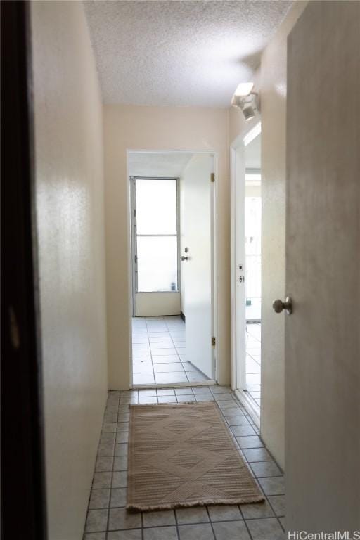 corridor with light tile patterned flooring and a textured ceiling