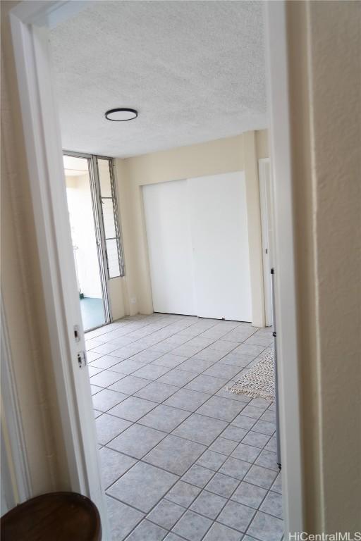 corridor featuring a textured ceiling and light tile patterned floors