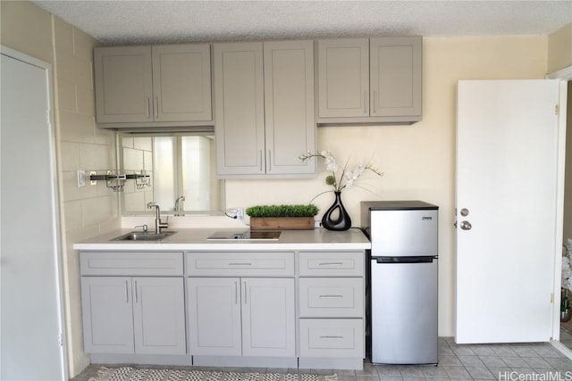 kitchen with sink, gray cabinets, a textured ceiling, and stainless steel fridge