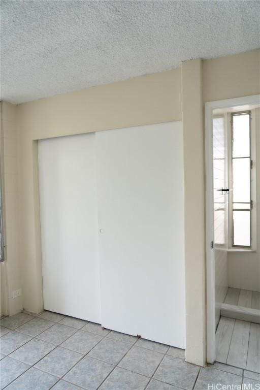 unfurnished room featuring plenty of natural light, a textured ceiling, and light tile patterned flooring