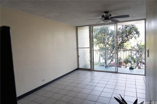 tiled empty room with ceiling fan, a textured ceiling, and a wall of windows