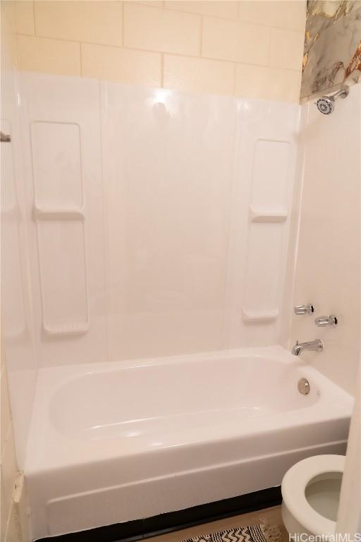 bathroom featuring tub / shower combination and toilet