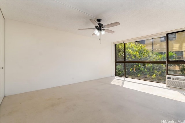 spare room featuring ceiling fan, cooling unit, a textured ceiling, and expansive windows